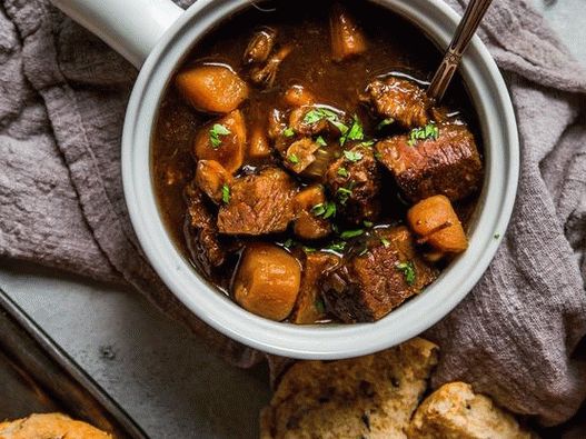 Photo Beef ribs stewed with root vegetables in dark beer