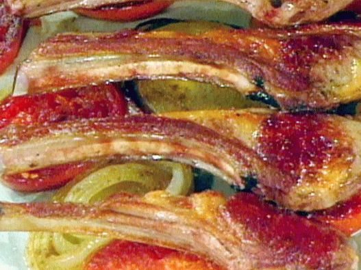 Photo of a rack of lamb on a pillow of spicy tomatoes and onions