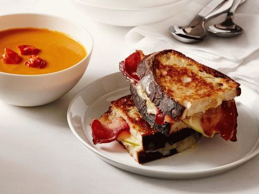 Photo Cream-soup of baked tomatoes and a sandwich with cheese and bacon