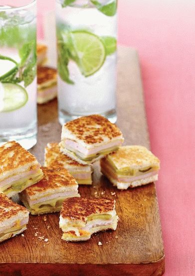 Photo of a Cuban sandwich stuffed with pork tenderloin and ham, with banana chips and mojito