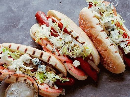 Hot dogs with beef sausages, gorgonzola cheese, tomatoes, onions and frize salad