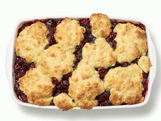 Photo of a peach cobbler with raspberries under a dough lid