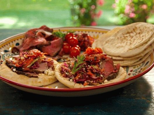 Photo of Pita with lamb in pomegranate glaze with mint on a spit, grilled tomatoes and Greek cabbage salad
