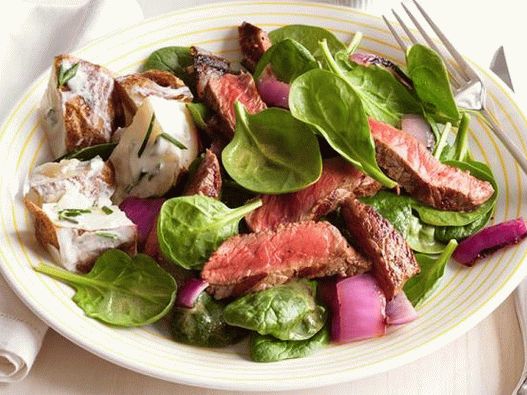 Photo sirloin steak and grilled onions with spinach and potatoes in sour cream