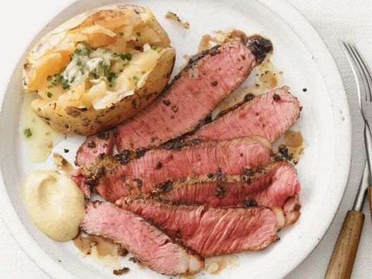 Photo steak sirloin under a crust of provencal herbs and a side dish of baked potatoes